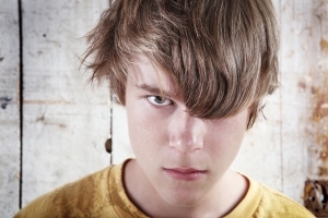 A troubled teen peers through his hair.